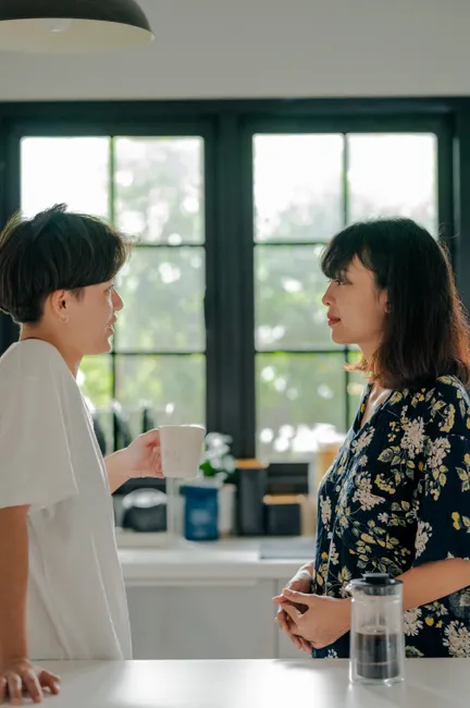 Two adults chatting over coffee in a cozy kitchen setting, capturing a warm morning moment.