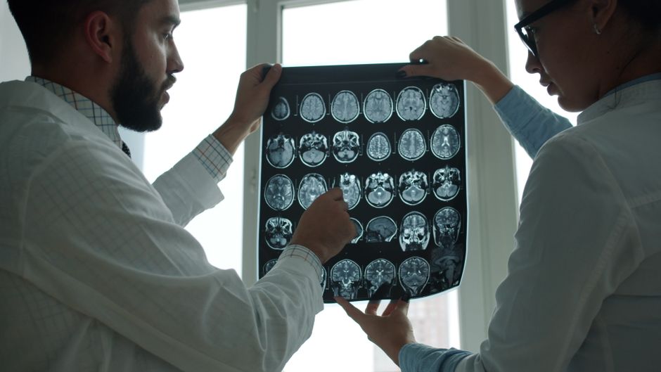 Amour romantique et cerveau : 6 mythes, sans diagnostic express Two doctors examining MRI brain scans in a well-lit hospital room.