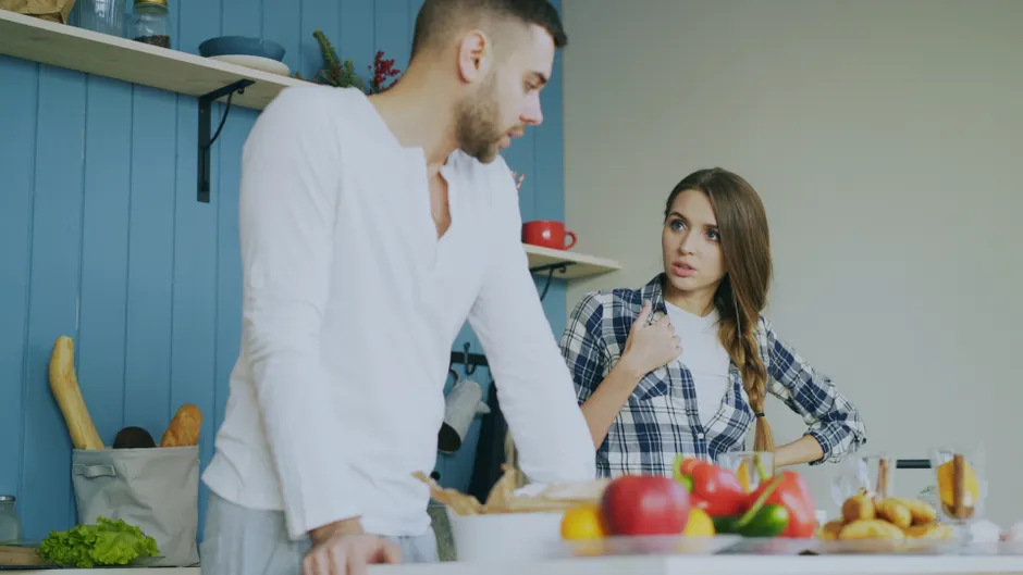La flamme du couple ne meurt pas au lave-vaisselle: 5 gestes pour la relancer Young couple engaged in a conversation in a stylish kitchen with fresh fruits.