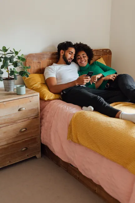 Young couple enjoying a relaxing moment on their bed with a mobile phone.