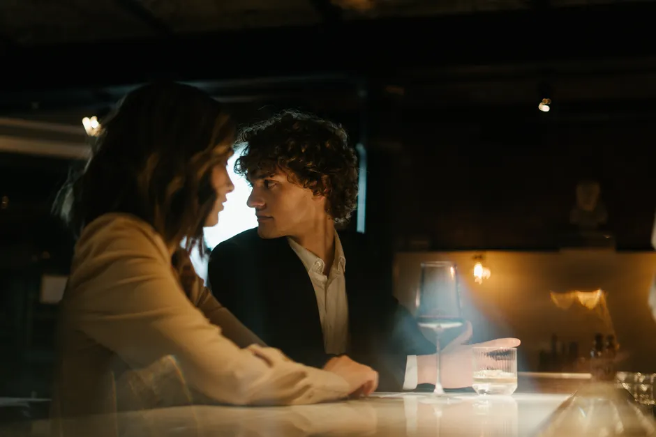 Coach relationnel : 5 repères avant de se lancer, sans gourou Young couple enjoying a romantic evening at an elegant bar. Warm lighting sets a cozy atmosphere.