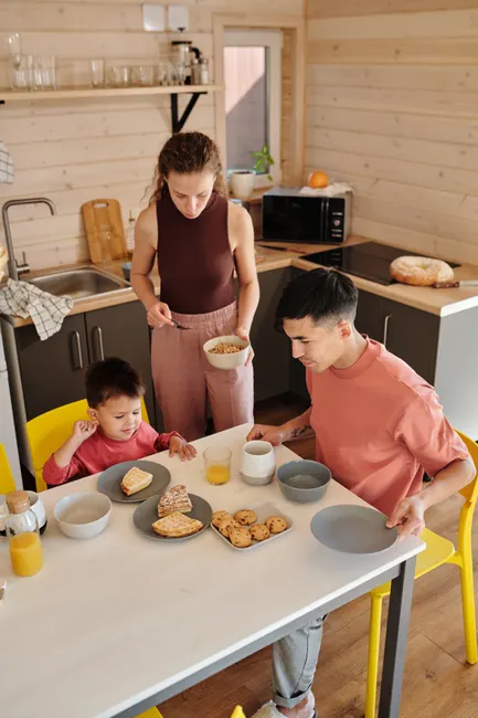 A family breakfast scene in a modern kitchen with parents and child enjoying a meal together.