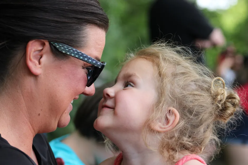 A joyful mother and daughter share a tender face-to-face moment outdoors, smiling lovingly.
