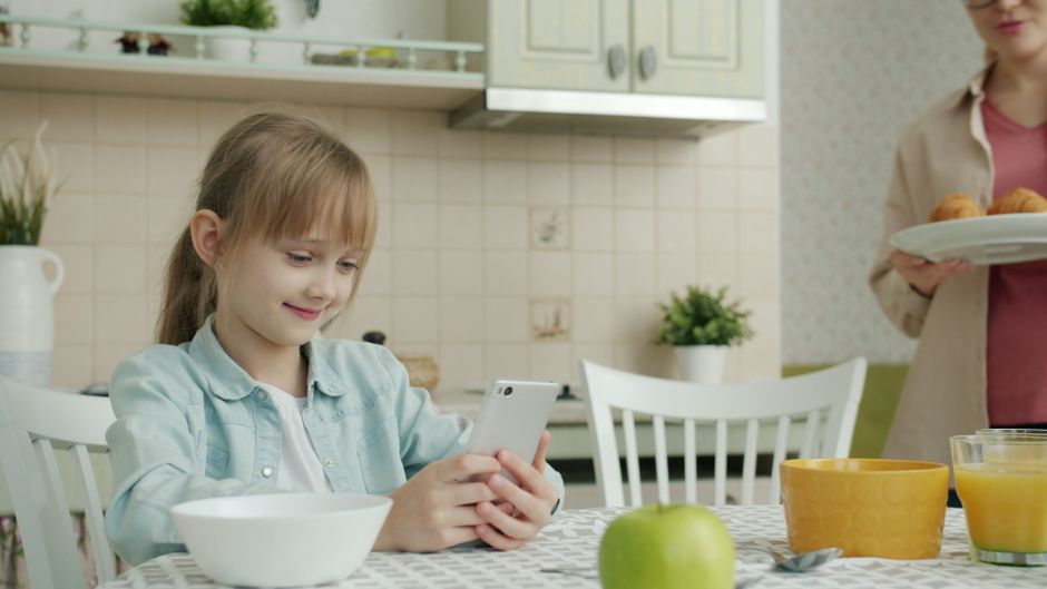 Se dévoiler en ligne et dans le couple : 5 repères, sans forcing A young girl enjoys using a smartphone at the kitchen table. Morning routine.