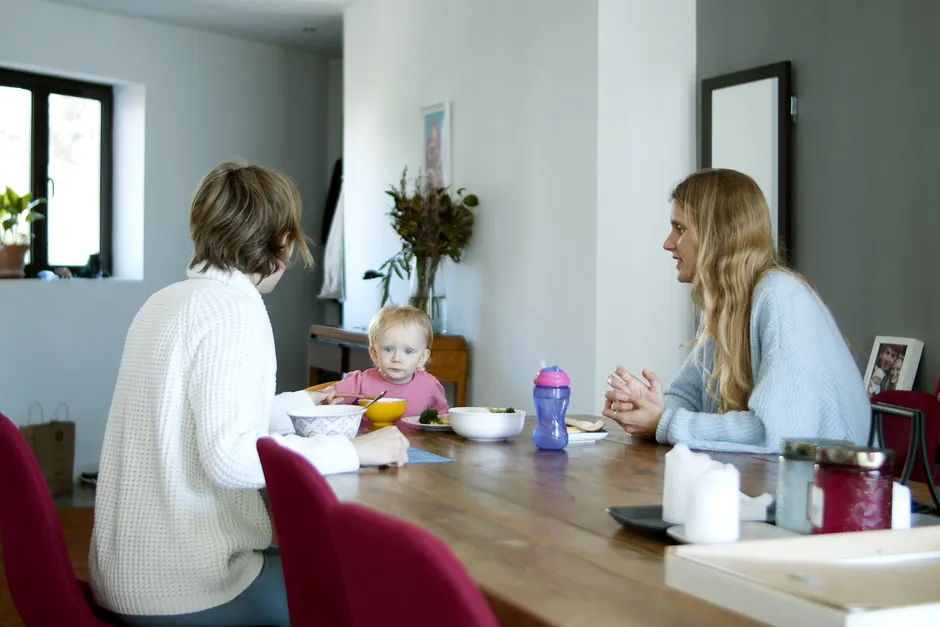 Quand le couple passe en batterie faible: 5 réglages de communication pour parents débordés Casual family dining scene with parents and child at home in Portugal.