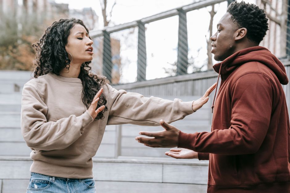 Communication dans le couple : 4 études et le piège du silence Side view of ethnic woman with outstretched arms trying to stop African American man while breaking up on street in city